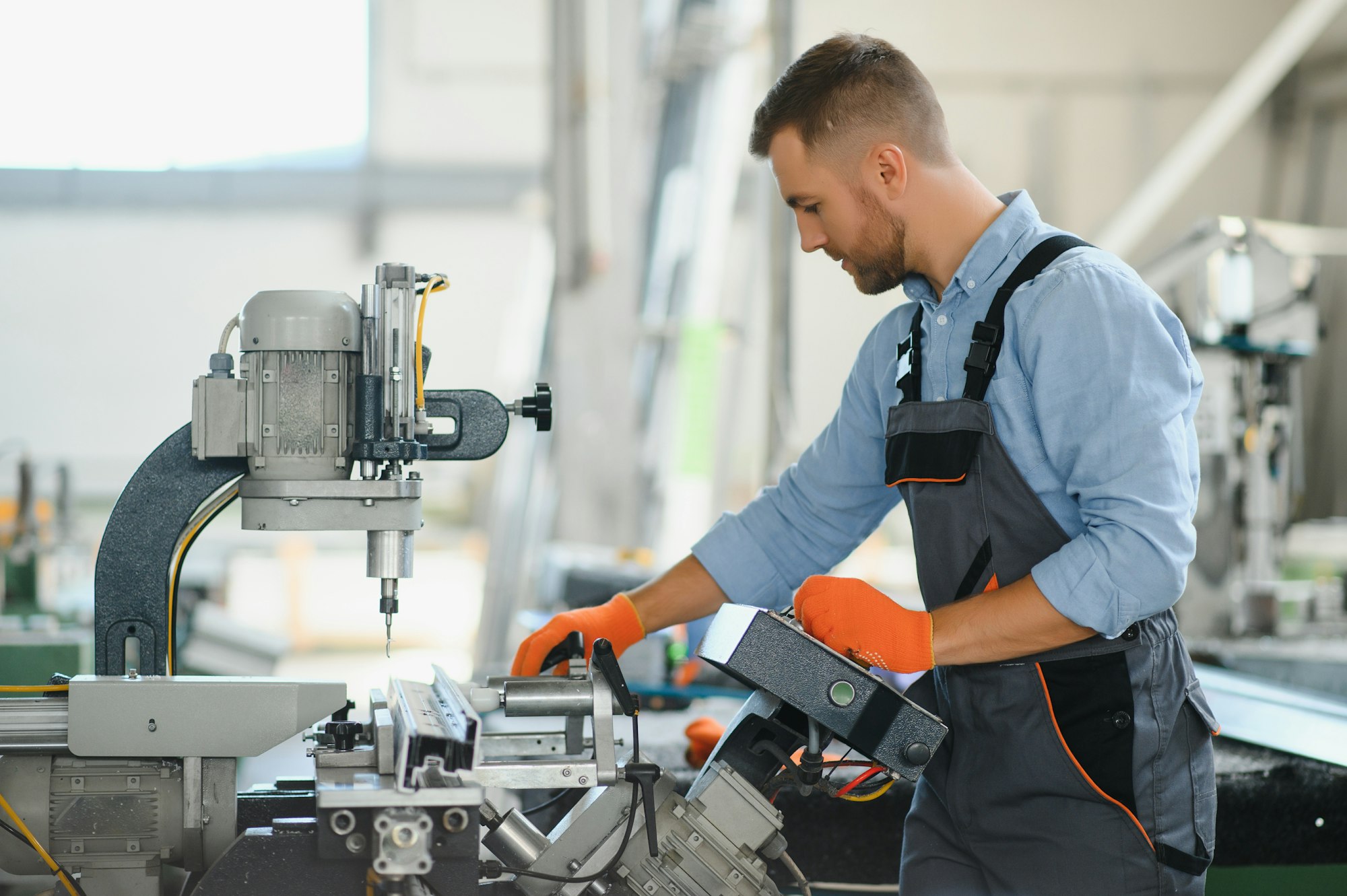 Male factory mechanics or Engineer in safety uniforms are working on metal drilling machines